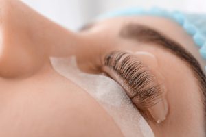 Young woman undergoing procedure of eyelashes lamination in beauty salon, closeup